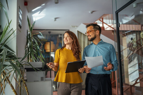 Business colleagues collaborating walking through office hallway