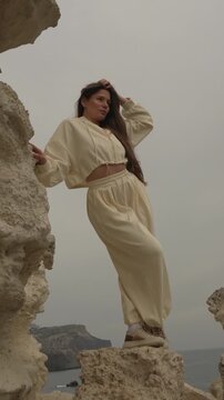 Woman cliff ocean young woman wearing beige tracksuit posing on a high limestone rock overlooking the sea on a foggy day