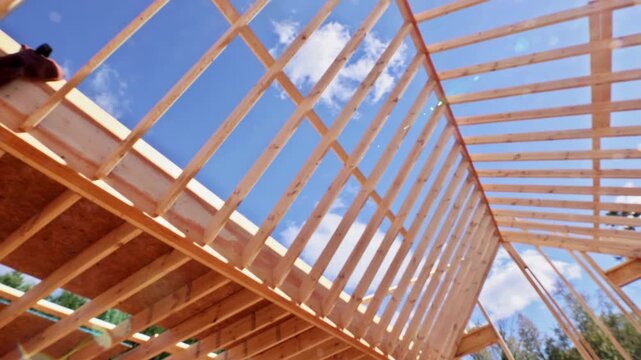 Workers build wooden frame for roof truss under beams joist studs