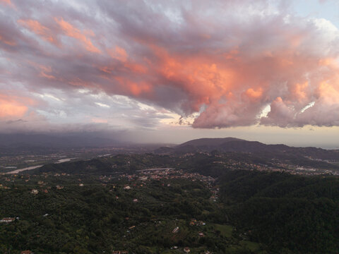 Aerial view of the town of Vezzano Ligure nestled in the rolling green hills under a dramatic sunset sky with pink clouds in Vezzano Ligure, Liguria, Italy.
