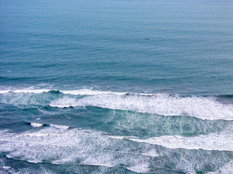 Aerial view of the Indian Ocean coastline with turquoise waves crashing against the shore in Bantul, Special Region of Yogyakarta, Indonesia.