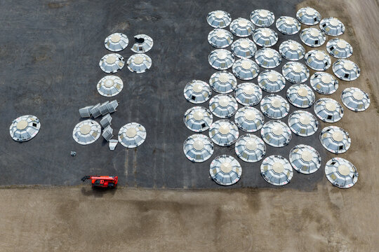 Aerial view of numerous prefabricated stainless steel storage tank roofs arranged in rows on a paved industrial site in North Holland, Netherlands.