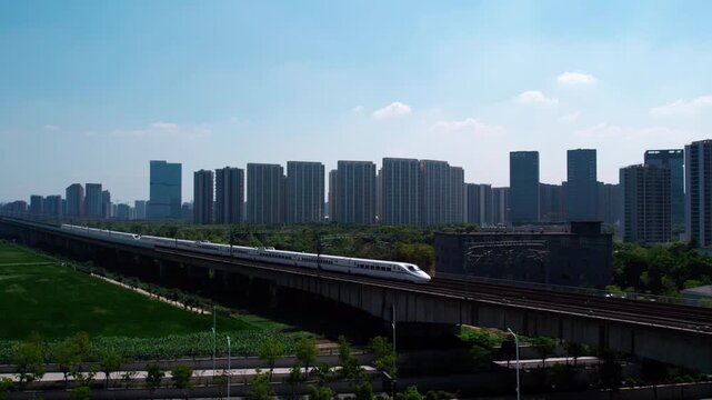 A modern urban landscape featuring high-rise buildings, an elevated railway, and green spaces under a clear blue sky.