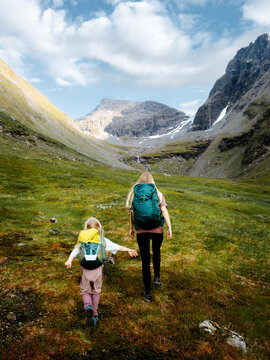 Family mother and child hiking together active travel in Norway, parent and kid on camping vacations tour in Lyngen Alps outdoor summer holidays people trekking with backpacks eco tourism
