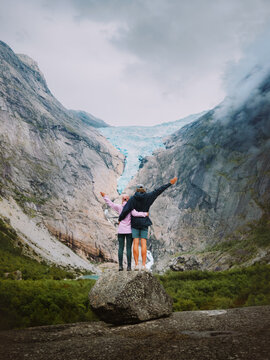 Couple hugging with Briksdalsbreen glacier view in Norway, man and woman in love travel together enjoying romantic vacation in mountains friends on hiking adventure trip family bonding moments