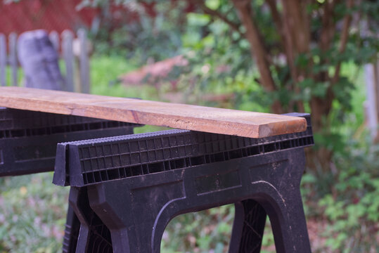Wooden Board Resting on Sawhorses Outdoors back view