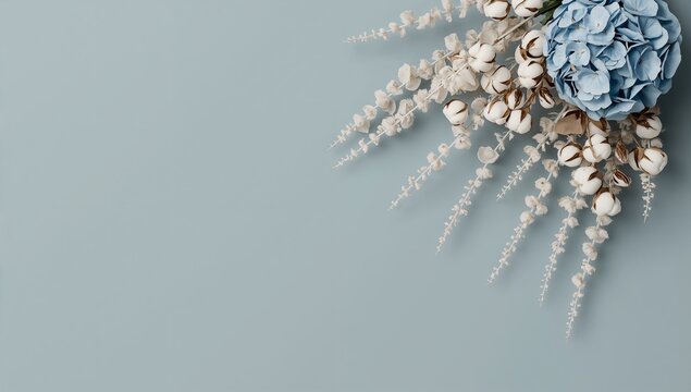 Delicate floral arrangement featuring light blue hydrangea flowers and fluffy white cotton bolls with dried foliage on a soft blue background for a serene aesthetic.