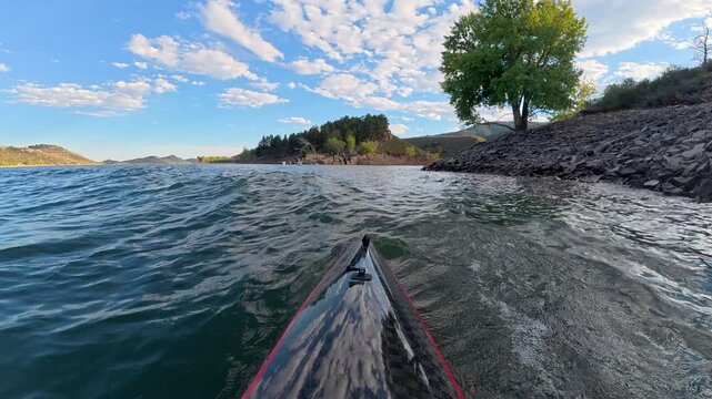 Immersive POV kayaking across Horsetooth Reservoir in Fort Collins, Colorado - summer scenery as a carbon fiber kayak cuts through boat-driven waves, surrounded by the scenic foothills of the Rocky Mo