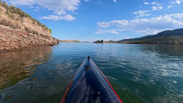 Immersive POV kayaking across Horsetooth Reservoir in Fort Collins, Colorado - summer scenery as a carbon fiber kayak glides on a calm water, surrounded by the scenic foothills of the Rocky Mountains 