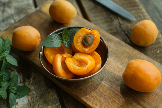 Fresh apricots decorated with mint leaves on wooden cutting board