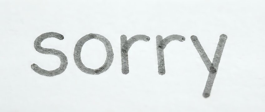 Textured gray word sorry written on white surface, conveying apology