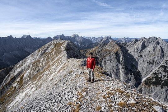 Mountain panorama, mountaineer on the ridge of the Gamsjoch, transition to the main summit of the Gamsjoch, behind western summit with summit cross, behind mountain ridge of the Hinterautal-Vomper chain, in autumn, Ri&szlig;tal in the Eng, Karwendel, Tyrol, Austria