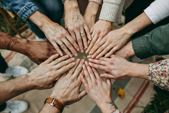 Diverse group of people joining hands together in a circle, symbolizing unity, teamwork, cooperation, community, and human connection concept