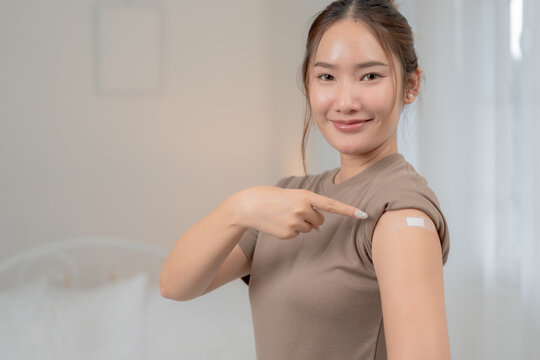 Vaccination, immunization and healthcare concept. Smiling young Asian woman shows a bandage on her upper arm after receiving a vaccine. Vaccination, vaccine, immunity, healthcare