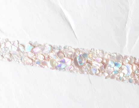 Pale pearlescent shell flakes forming a band on white paper, delicate abstract background