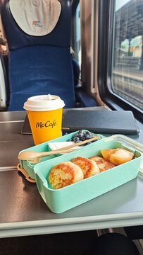 Gdansk, Poland - July 22, 2026: McDonald's McCafe coffee cup and breakfast box with pancakes, fruit, and blueberries on a train table with a window view