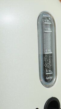 Dark fluid accumulates in transparent container reaching. Visible bubbles are present throughout rising volume. Vertical measurement device has visible labels for MAX MIN