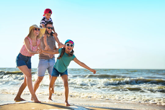 Happy family having fun on sandy beach near sea