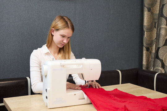 The young seamstress is using a sewing machine to create custom-made clothing.