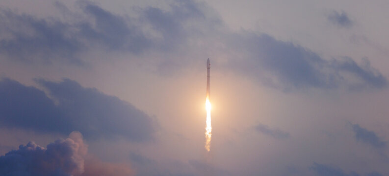 Rocket launching into cloudy sky at dusk with dramatic light. Banner of industry technology launching satellites into space