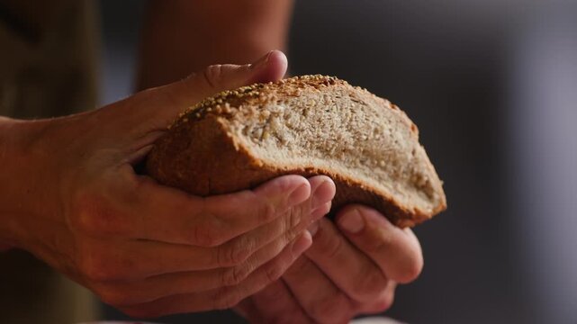 Bread multigrain loaf held in hands, whole wheat seeded crust with millet and seeds, close-up macro shot