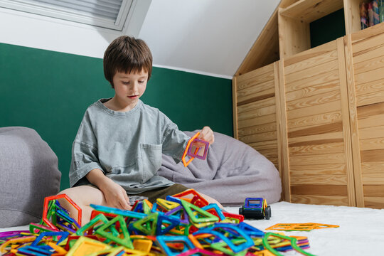 Young boy playing with colorful magnetic construction tiles