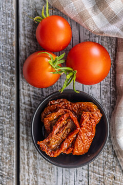 Close-Up Of Sun-Dried Tomatoes In Bowl With Fresh Tomatoes On Rustic Wooden Table
