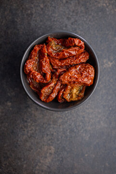 Sun-Dried Tomatoes in Olive Oil in a Bowl Over Dark Textured Surface, Mediterranean Ingredient