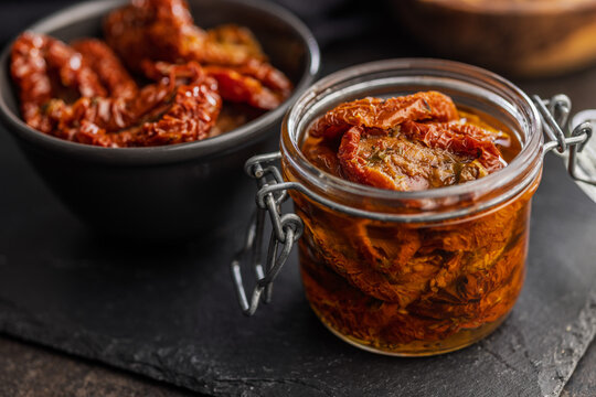 Sun-Dried Tomatoes in Jar with Olive Oil on Slate Board, Rustic Preserved Tomato Close-Up
