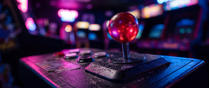 Retro arcade joystick close-up with neon lights in vintage video game arcade