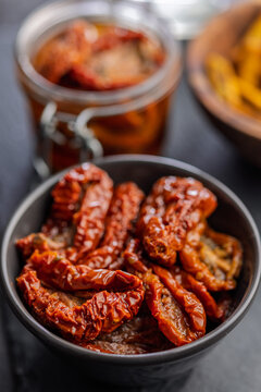 Sun-Dried Tomatoes in Olive Oil Jar and Bowl on Dark Slate for Gourmet Mediterranean Cooking