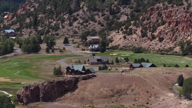 Aerial of American Flag on bluff in South Fork Colorado overlooking homes on golf course