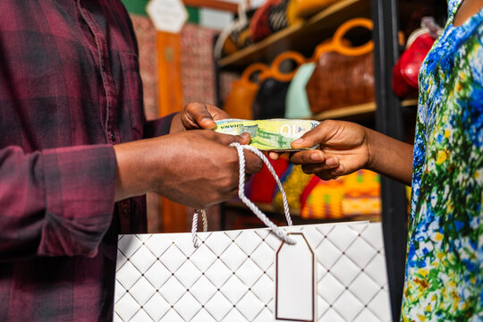 African customer making cash payment for a handbag purchase in a store