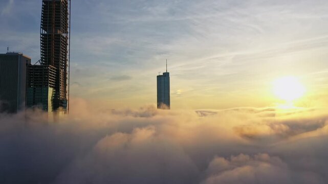 Aerial Descending Into Dense Fog Around City Skyscrapers at Sunset