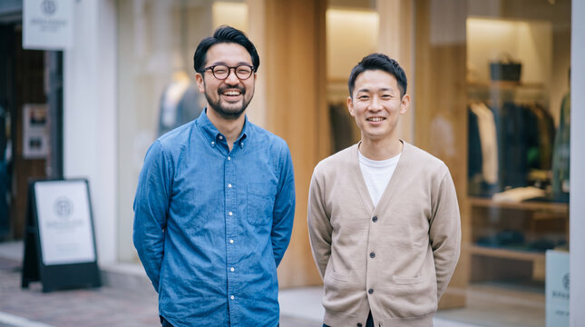 アパレル店舗の前で笑顔を見せる男性オーナーとスタッフ