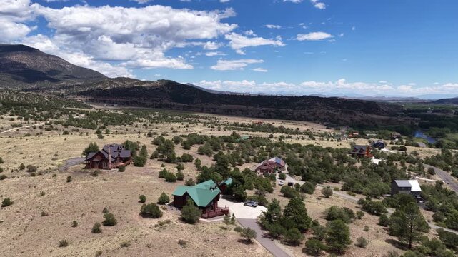 Aerial of rural residential community near South Fork Colorado in summer with scattered houses and properties set in a semiarid landscape featuring open grassland and mountains
