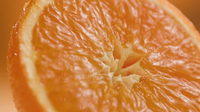 Orange fruit held in hand, fresh cut citrus close-up macro shot on orange background