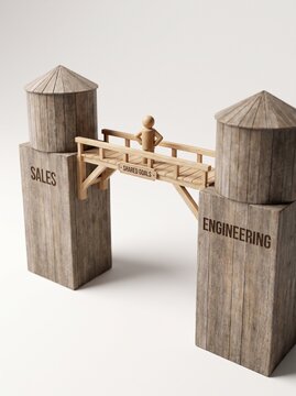 Wooden bridge labeled Shared Goals connecting Sales and Engineering towers with a small figure, representing cross-departmental collaboration and breaking down organizational silos