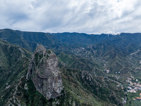 Aerial view of the dramatic volcanic rock formation of La Palma surrounded by lush green mountain slopes and deep valleys in the Canary Islands, Spain.