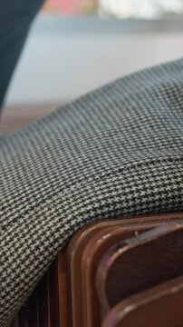 Close up of wooden chairs with parallel slats. Black and white houndstooth patterned cloth draped over edge is shown. Scene features natural light outdoors or semi outdoor space