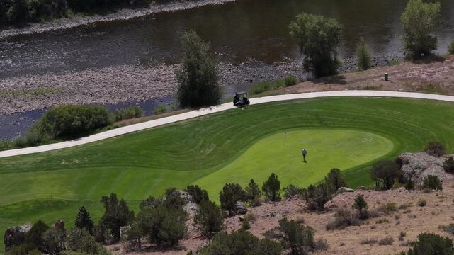 Aerial of golf course in South Fork Colorado on Rio Grande River with golfer with manicured green fairway in summer