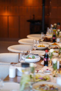 A long wedding table with dishes, glasses, flowers, and food creates an elegant atmosphere for a festive reception.