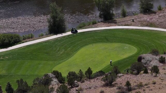 Aerial of golf course in South Fork Colorado on Rio Grande River in summer featuring a golfer on the green and golf cart
