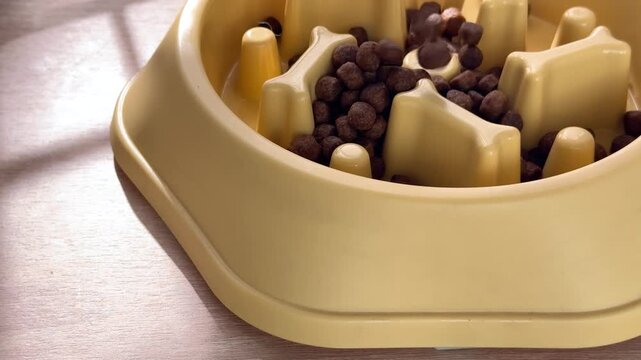 Pouring dry kibble into a yellow slow feeder dog bowl