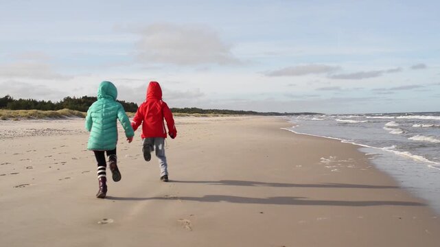 Two sisters walking along shore of Baltic Sea