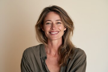 Obraz premium Warm studio portrait of a smiling woman with fair hair in casual clothing against a neutral backdrop