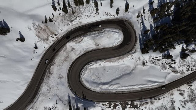 Cars Driving on Winding Asphalt Road Through Pine Forest and Mountain Landscape in winter aerial drone 4k video