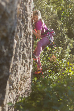 Young woman confidently rock climbing enjoying outdoor sport