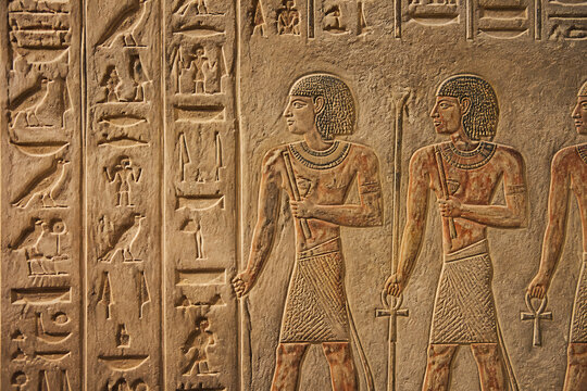 Ancient Egyptian relief carving depicting figures in traditional attire standing side-by-side.