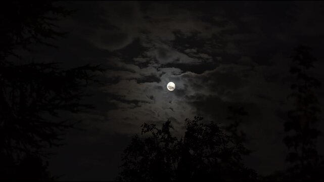 A glowing full moon in the dark and cloudy night